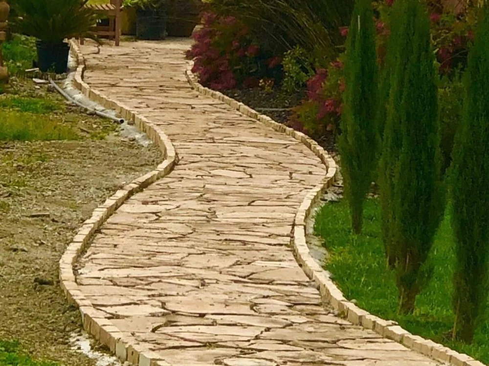 Curving flagstone walkway edged with a set stone border by Aguilar and Sons Construction