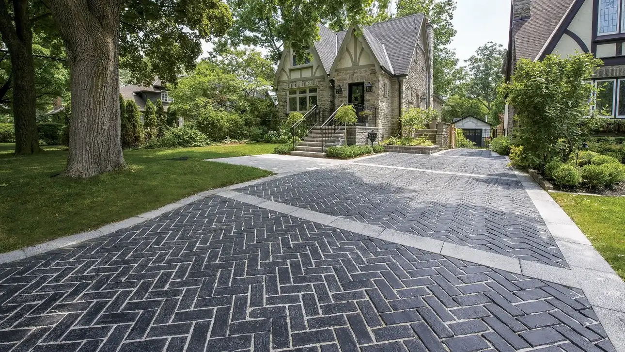 Paver driveways in a herringbone pattern: a charcoal drive framed by light border bands
