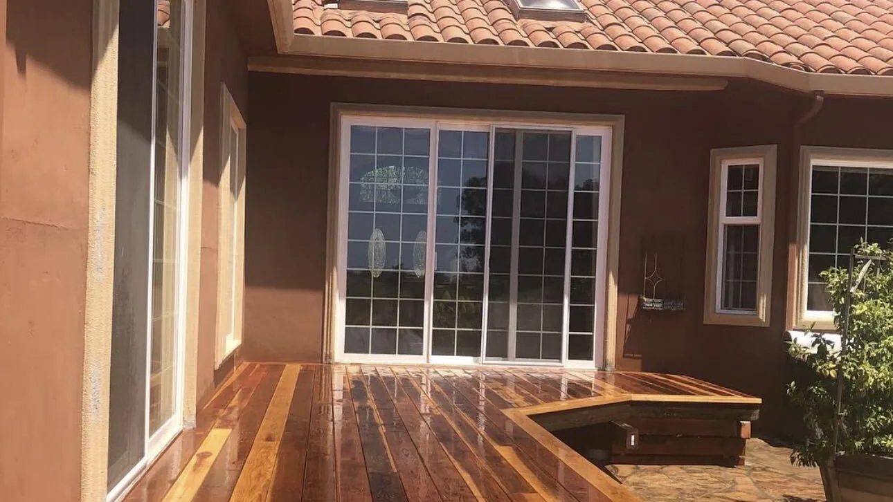 Wide redwood deck running the length of a stucco house by Aguilar and Sons Construction