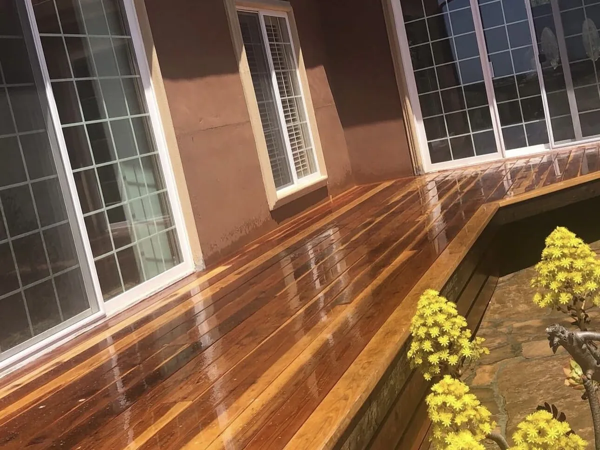 Wet redwood deck wrapping a stucco house beside flowering succulents